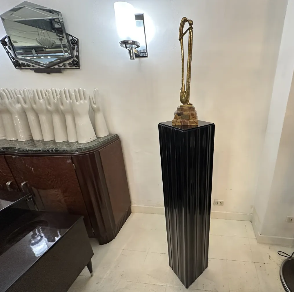 Antique decorative column topped with a sculpture, surrounded by white hands.