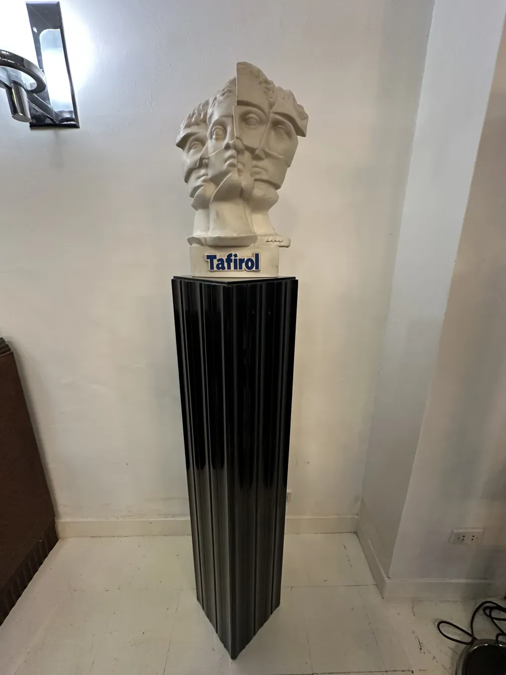 Coluna antiga com escultura no topo, ambiente elegante.