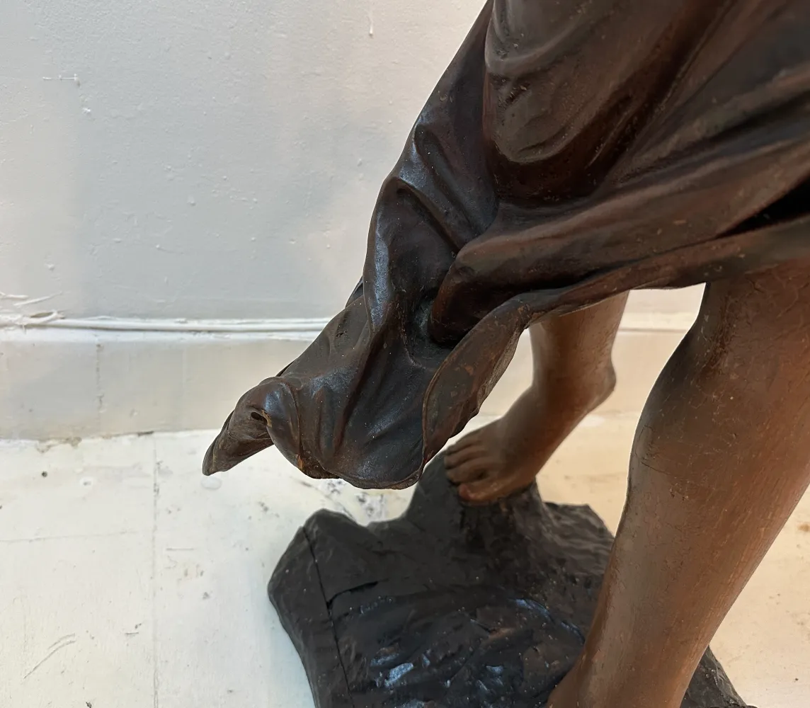 Scultura antica con statua realistica e dettagli fini nel tessuto.