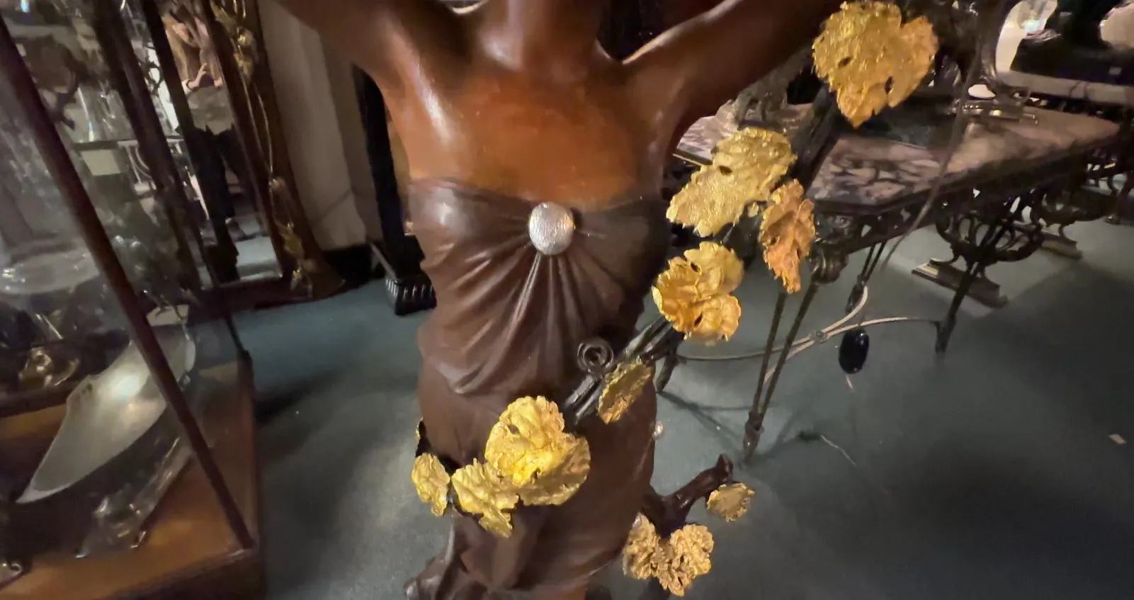 Escultura antiga de mulher com flores douradas em um ambiente elegante