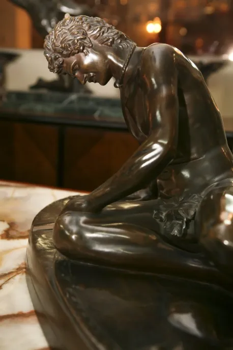 escultura antiga de um homem pensativo em um ambiente elegante