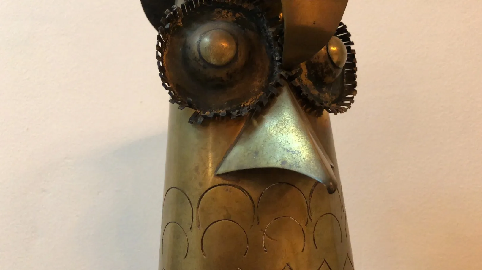 escultura antiga de uma coruja com detalhes metálicos distintos