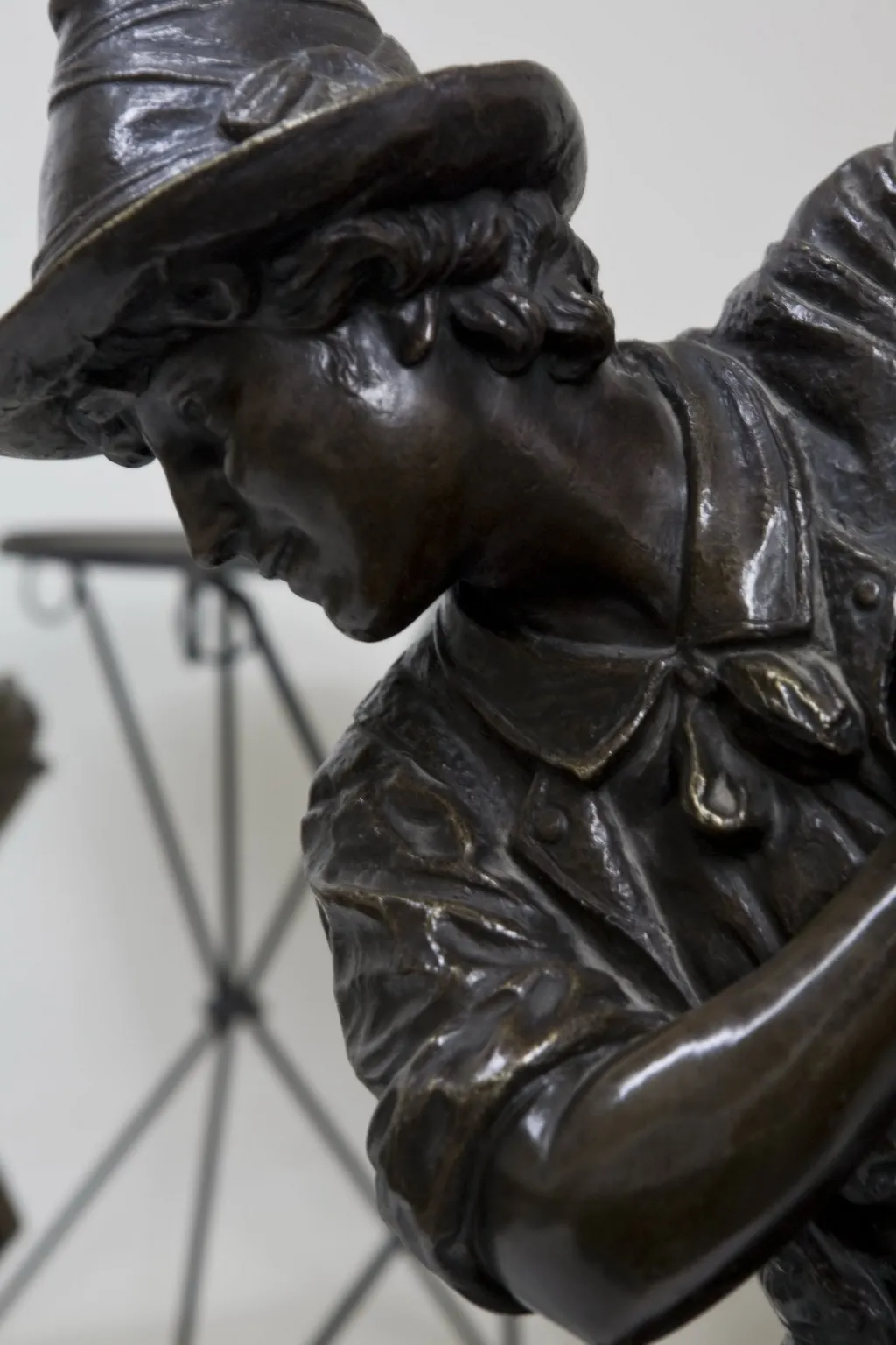 escultura antiga com detalhes em roupas e chapéu, ambiente artístico.