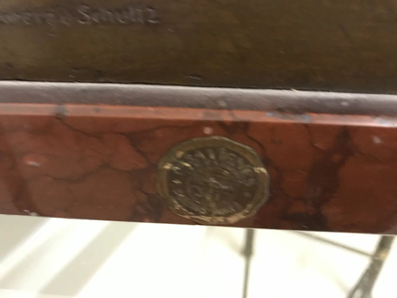 Escultura antiga com um selo de Guss Wollenberg Schuttz. Detalhes visíveis em um ambiente elegante.