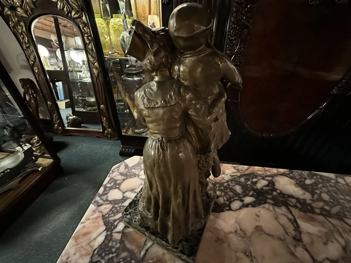 scultura antica di donna che tiene un bambino, dettaglio in bronzo, sfondo con vetrine e specchi