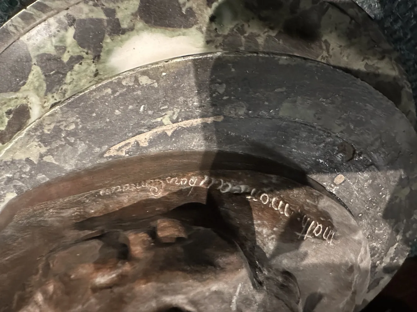 Detalhe de uma escultura antiga com inscrição visível.