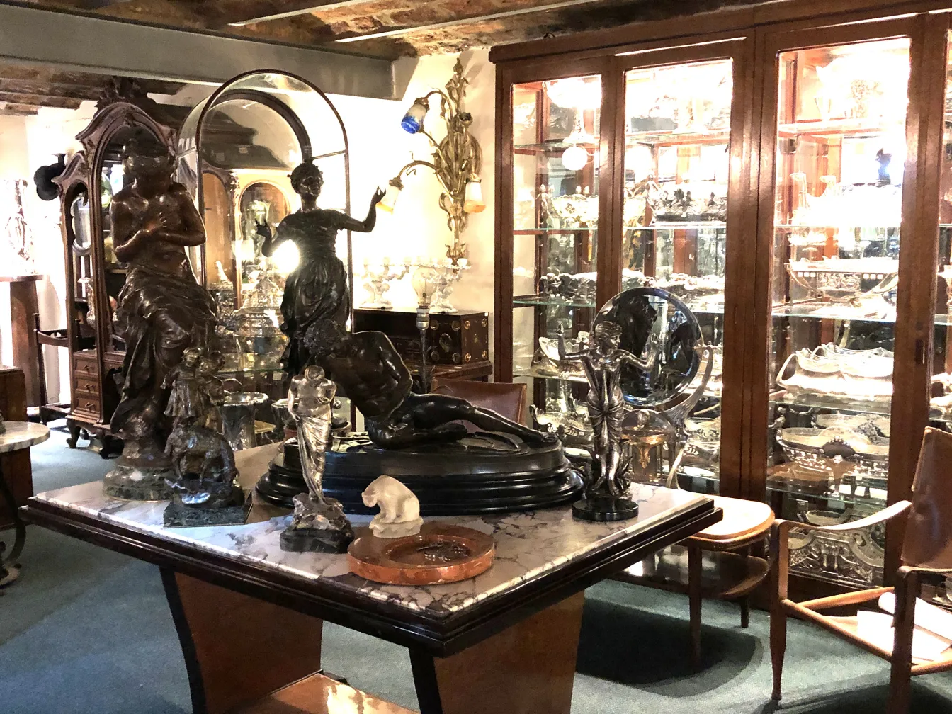 Various antique sculptures in an antique room with wooden furniture.