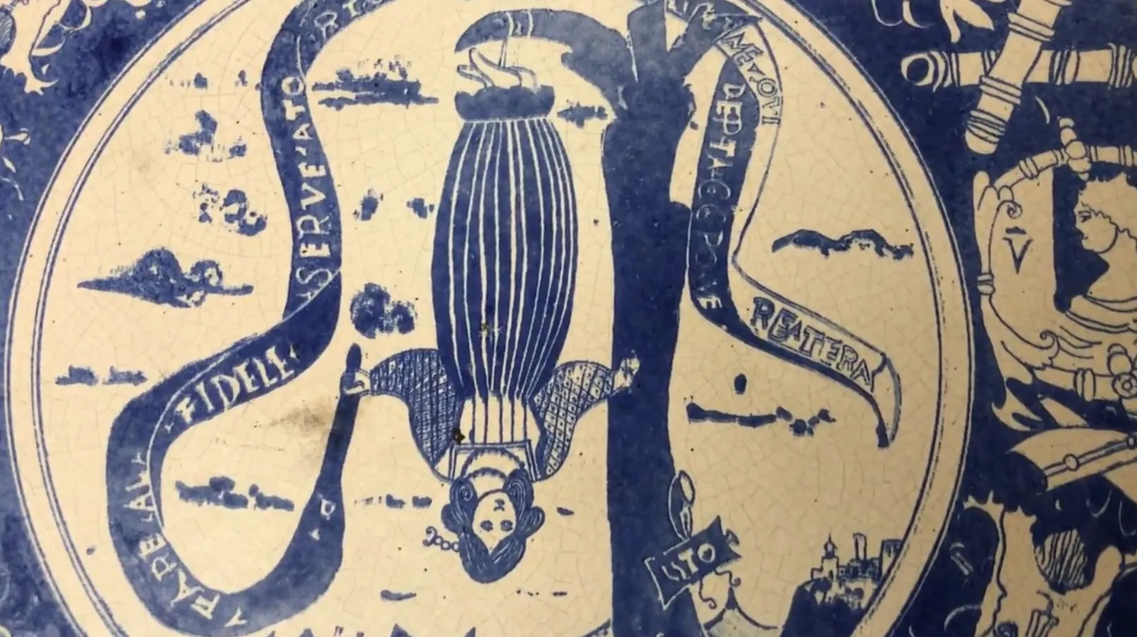 Piatto di ceramica antica con dettagli blu e figure dipinte.