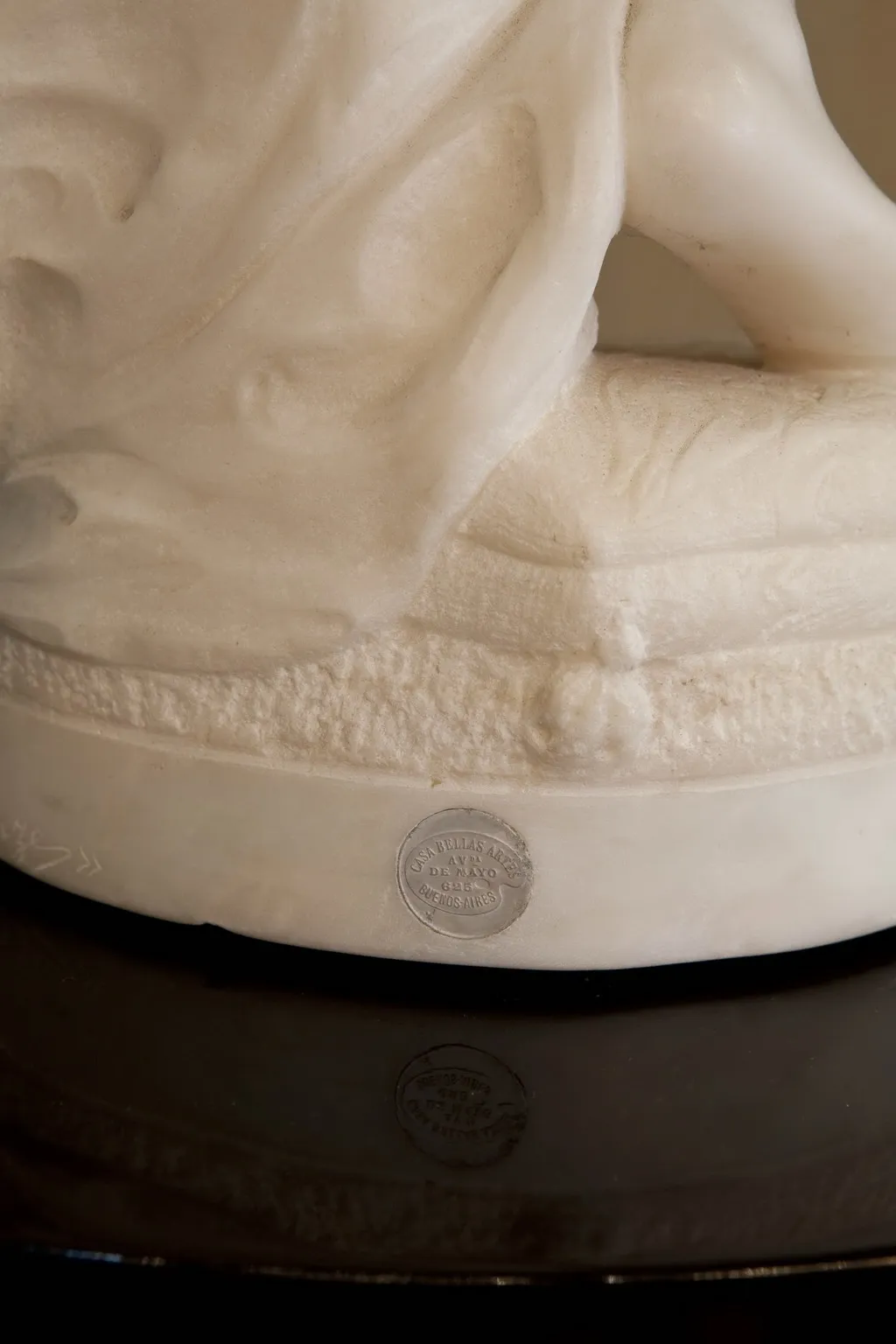 scultura antica con dettagli raffinati e volto sereno, posizionata su una superficie scura.