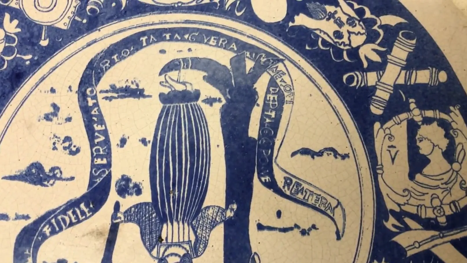 Plato de cerámica antigua decorado en azul y blanco, con adornos y detalles intrincados.