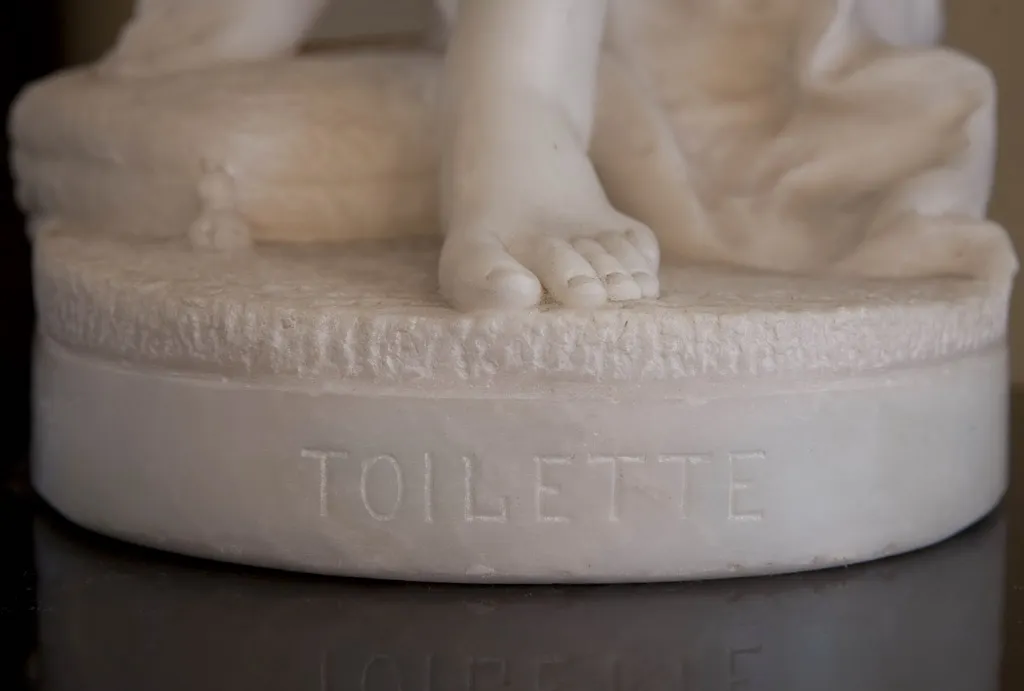 Scultura antica che rappresenta una toilette con dettagli intricati.
