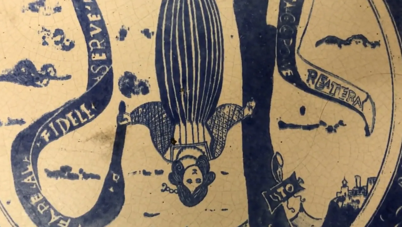 Cerâmica antiga com ilustração azul de uma mulher, detalhes intrincados.