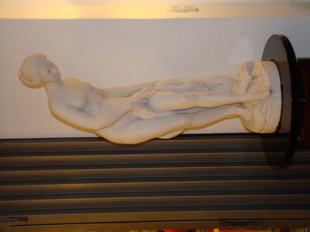 escultura antiga de mármore com figura feminina relaxada