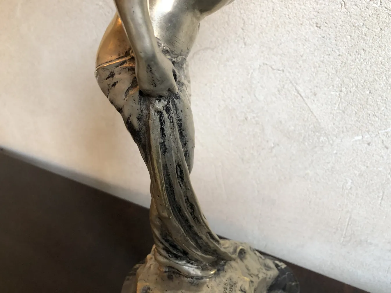 Escultura antiga de mulher em pose elegante, fundo neutro