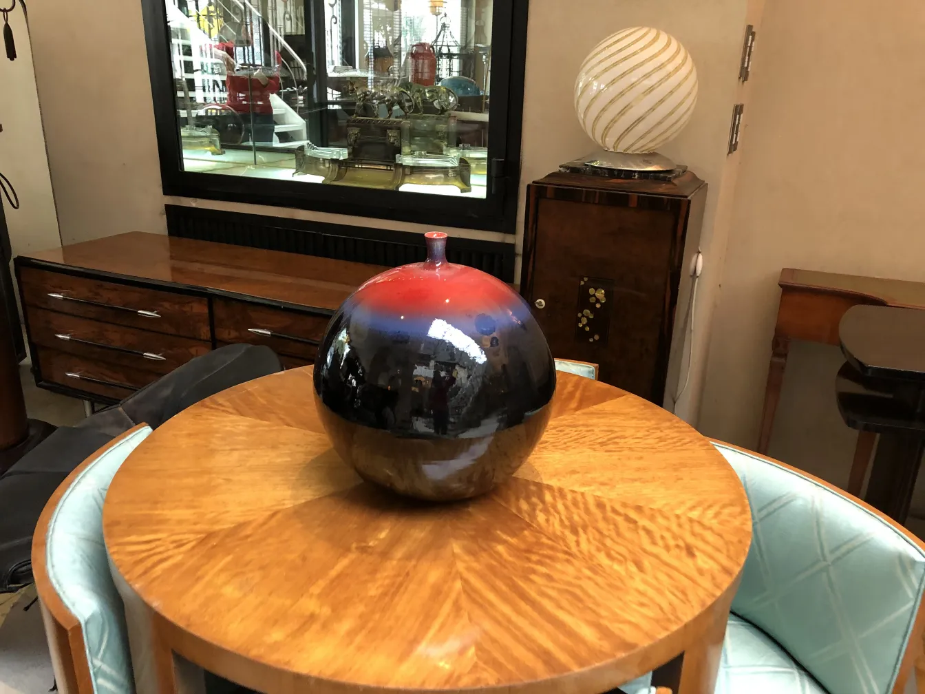 Antike dekorative Keramik-Sphäre in Schwarz-Rot auf einem Holztisch.