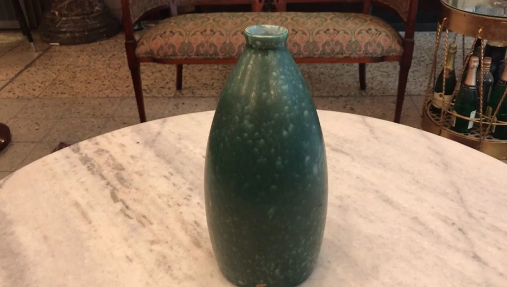 Cerâmica antiga decorativa com acabamento verde, em um ambiente elegante.