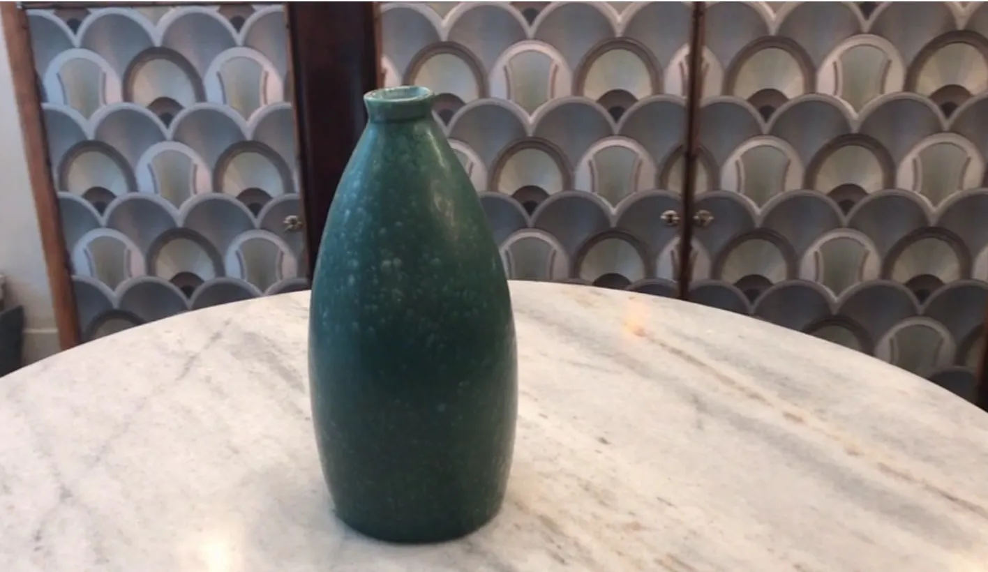Antique green ceramic vase on a marble table.