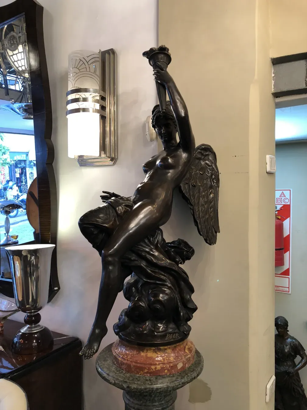 escultura antiga com figura feminina e asas, em um ambiente elegante