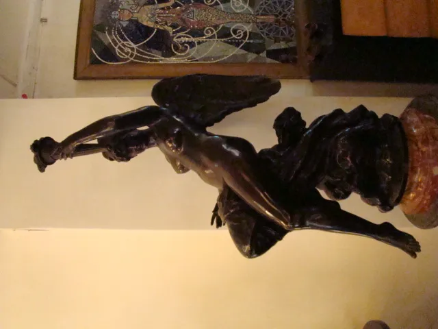 Scultura antica con figura femminile alata su un piedistallo.