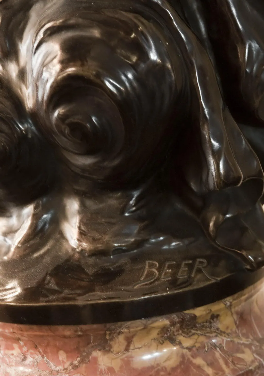 scultura antica con superficie liscia e dettagli fini, firma di beer visibile