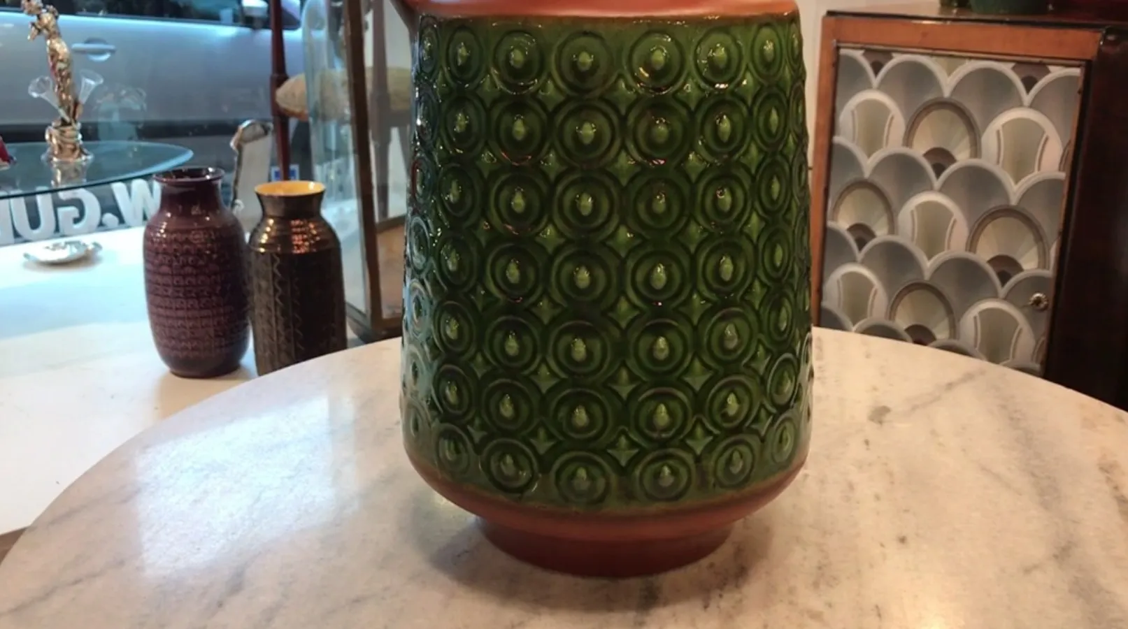 Jarrón antiguo de cerámica decorativa verde con patrón circular.