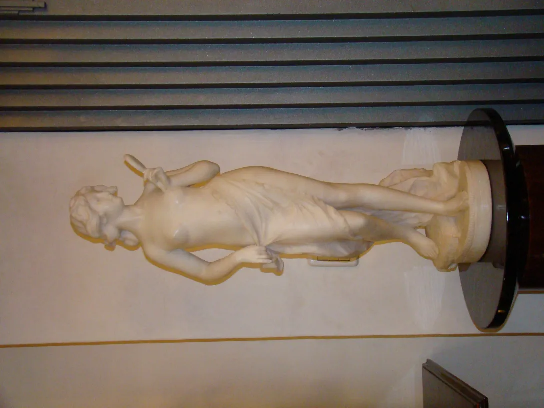 Escultura antigua de figura femenina en un entorno neutral.