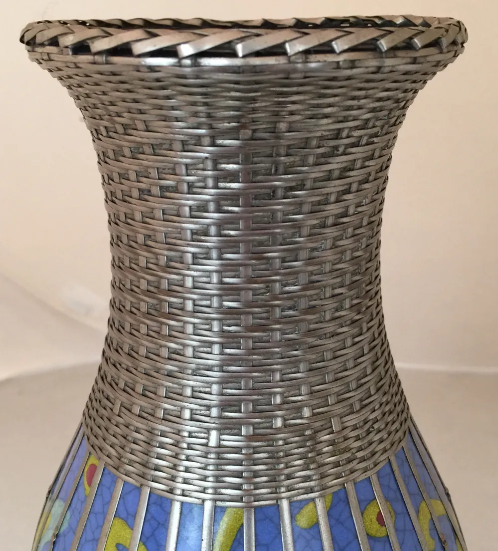 Vaso in ceramica antica con design colorato e texture intrecciata.