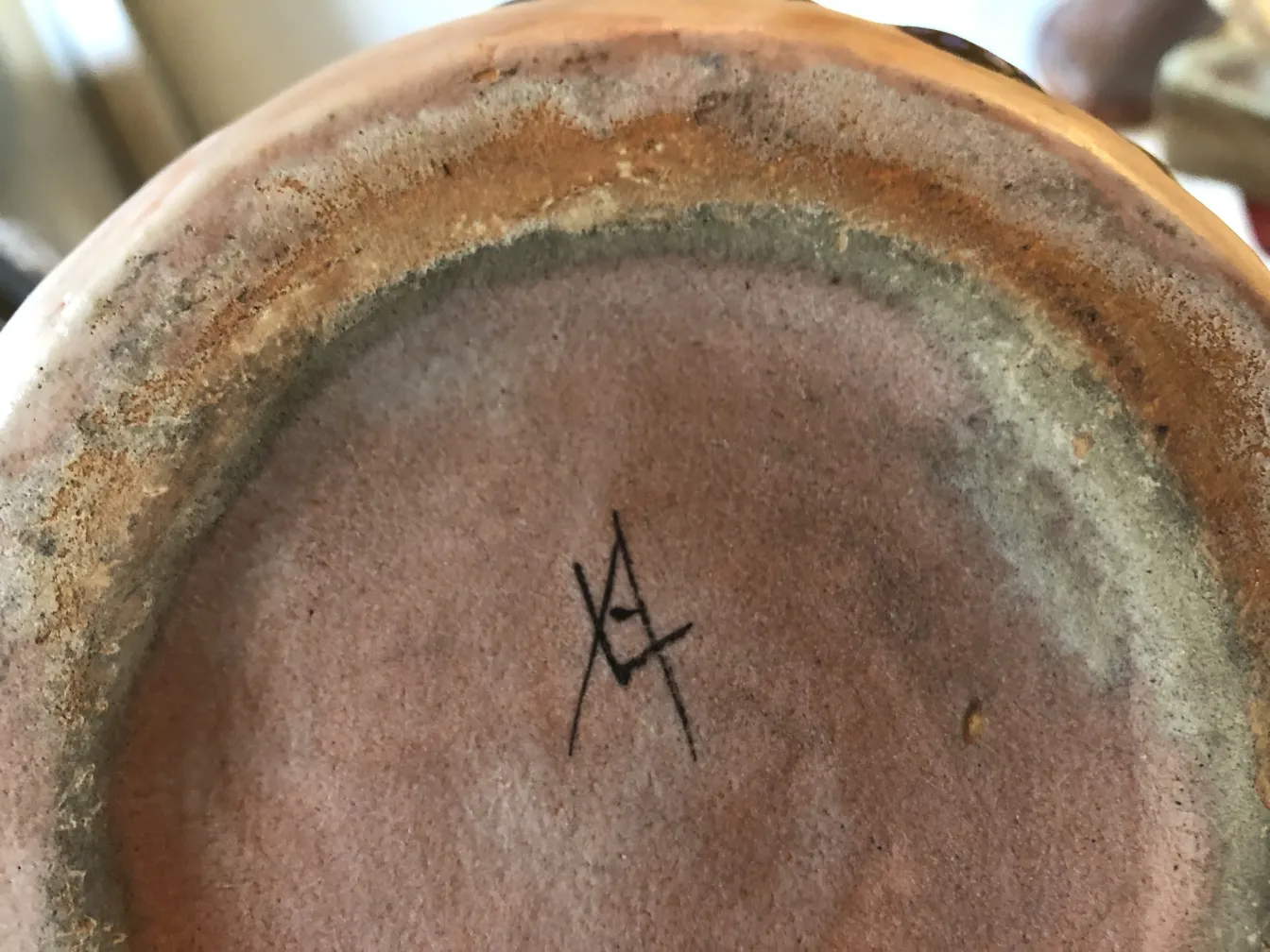 Ceramica antica con firma visibile, elementi decorativi sottili.