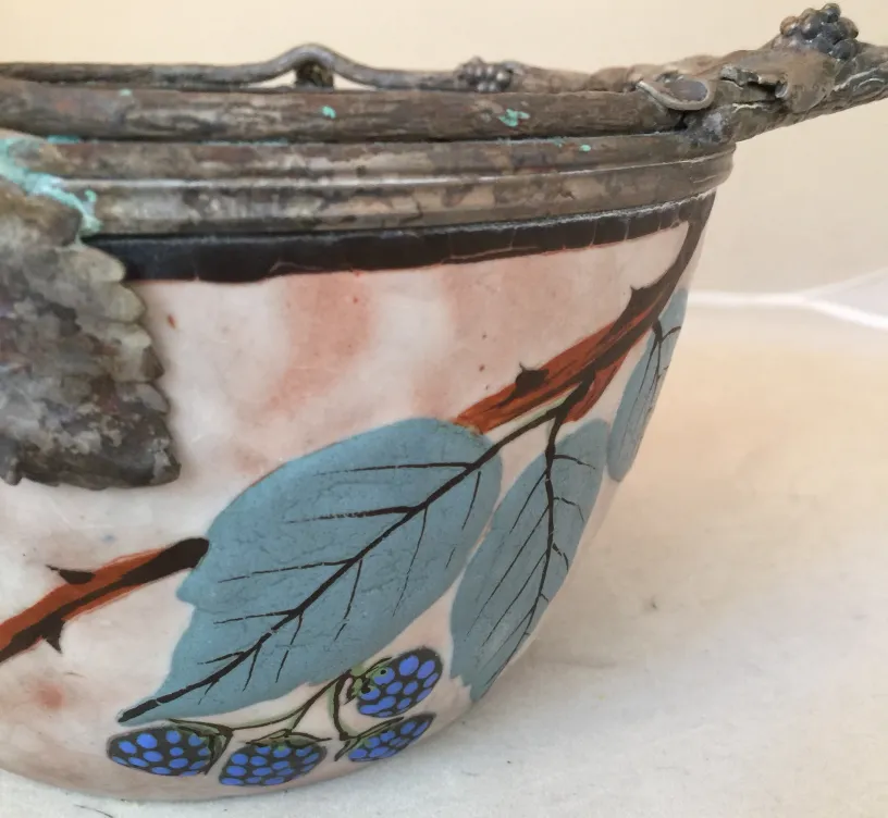 Antiga cerâmica decorada com folhas verdes e bagas azuis.