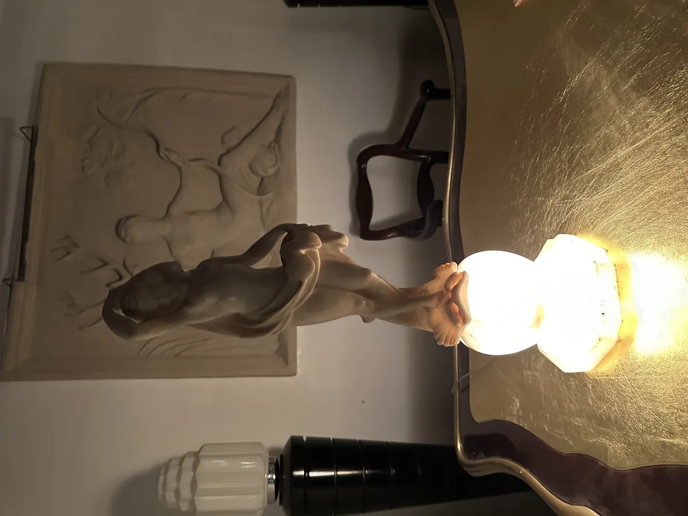 Escultura antiga de figura humana com fundo decorativo