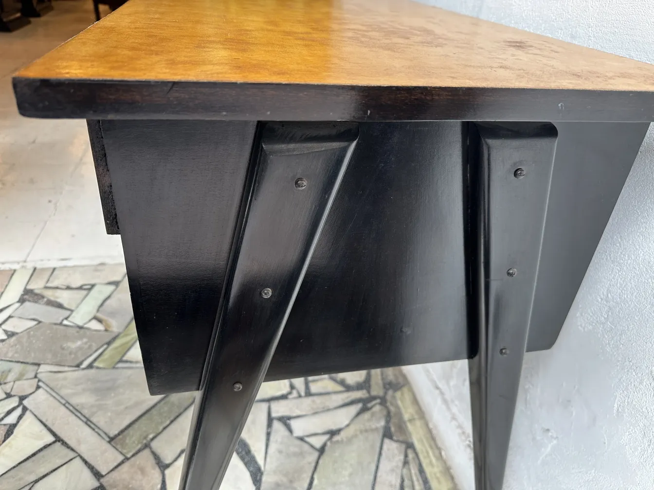 Scrivania antica con superficie in legno dorato e gambe nere.