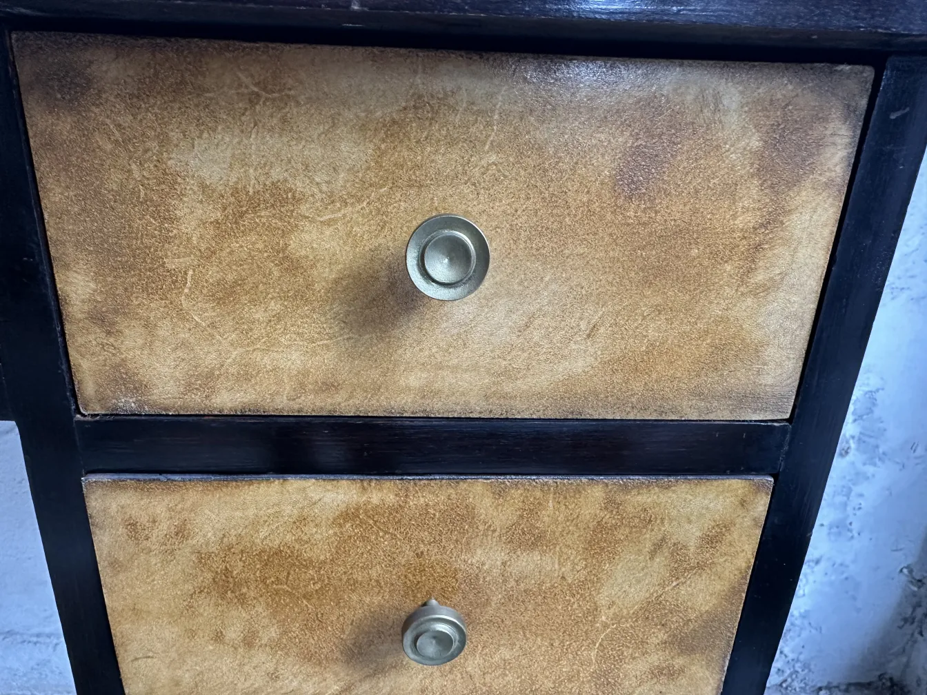 Antiker Schreibtisch mit heller Oberfläche und zwei bronzefarbenen Schubladen in einer neutralen Umgebung.