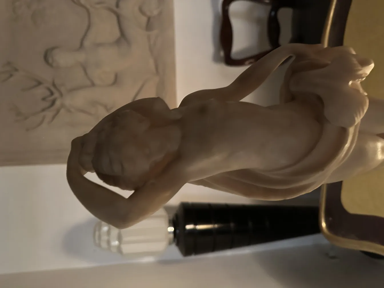 Escultura clásica con figura humana en detalle, fondo suave.