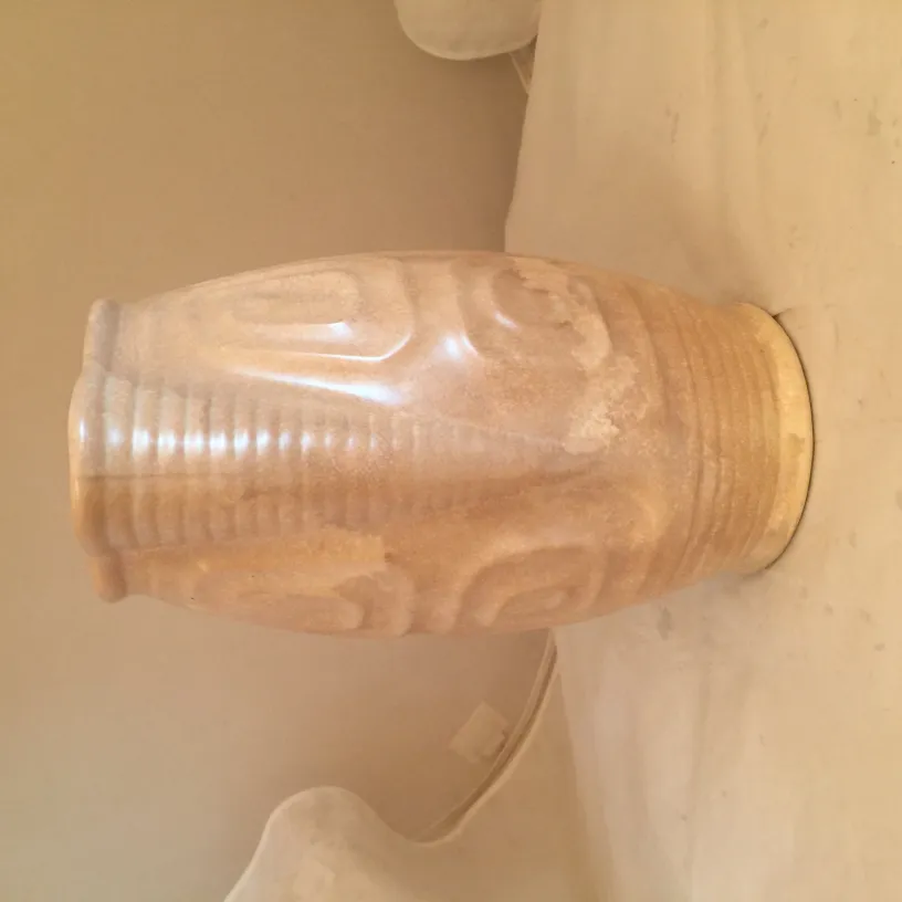 Antigua cerámica decorativa con diseños grabados, exhibida en un entorno neutral.