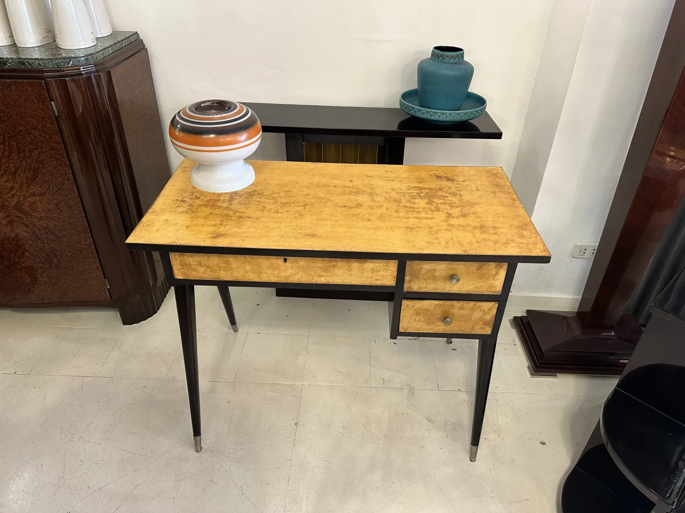 Escritorio antigo com tampo amarelo e duas gavetas, decorado com um vaso.