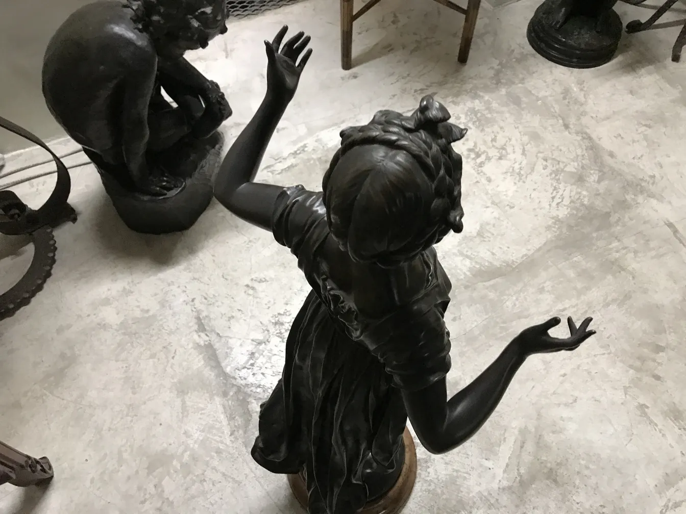 escultura antigua de niña con manos en alto en un ambiente clásico