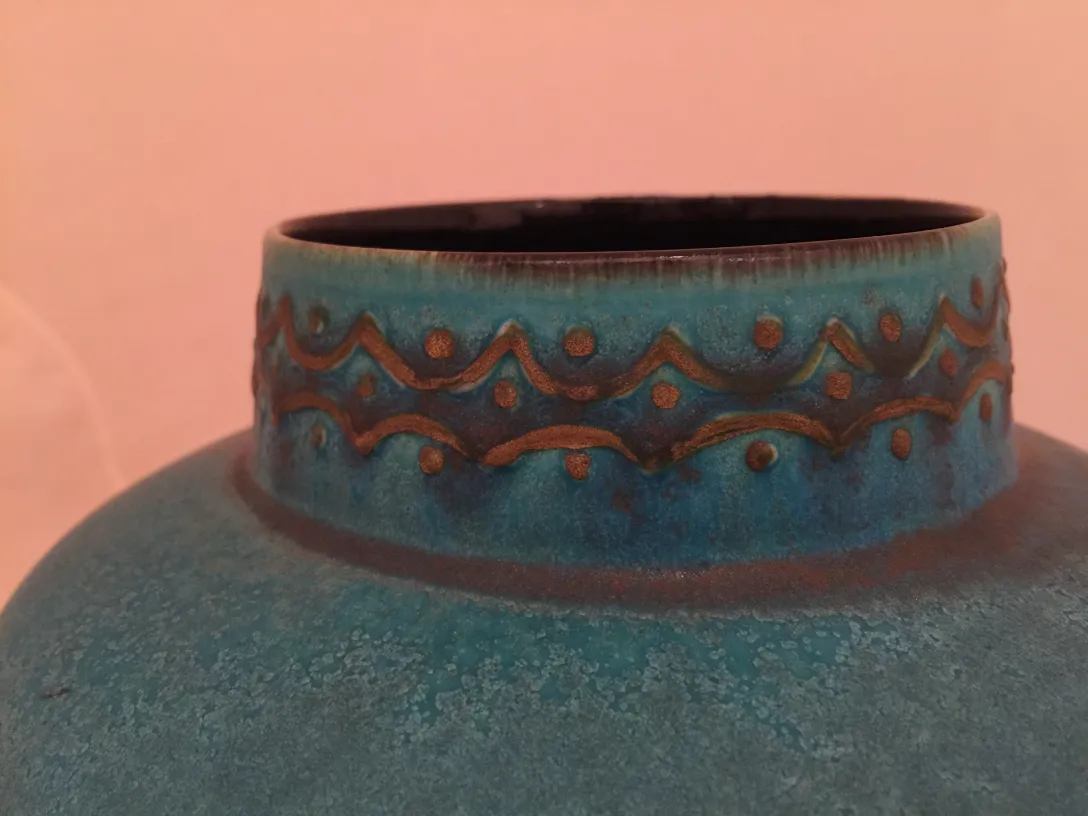 Vase en céramique ancienne de couleur bleue avec des motifs en relief.