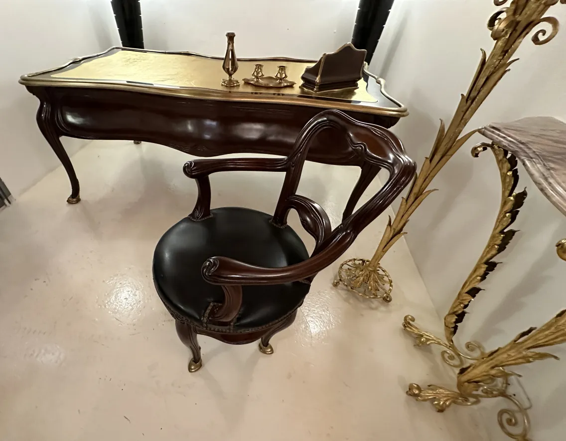 escritorio antiguo Gustave Keller con detalles de oro y diseño elegante, acompañado de una silla de juego en un espacio moderno.