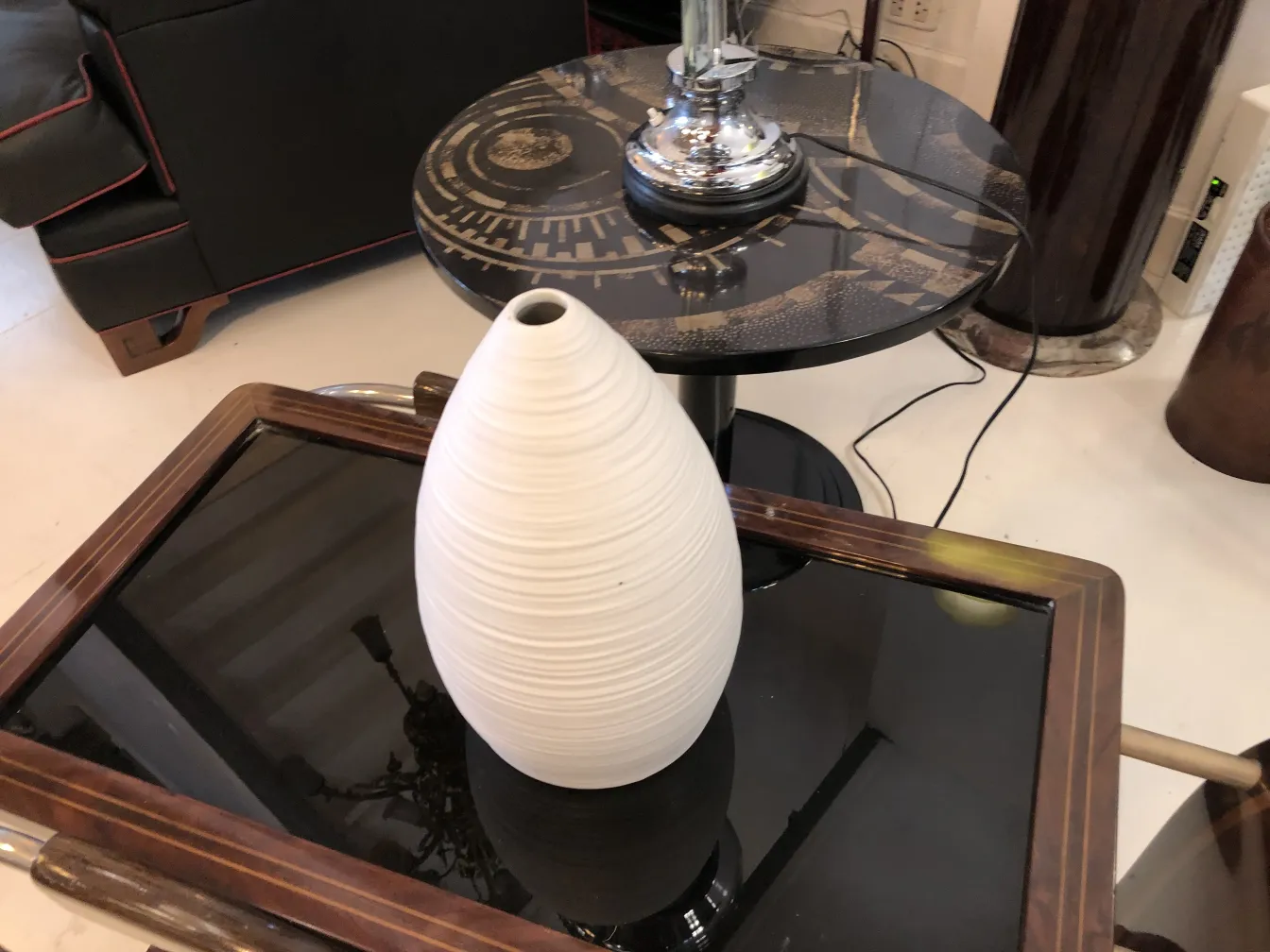 فازة سيراميك بيضاء بتصميم متموج على سطح زجاجي أسود