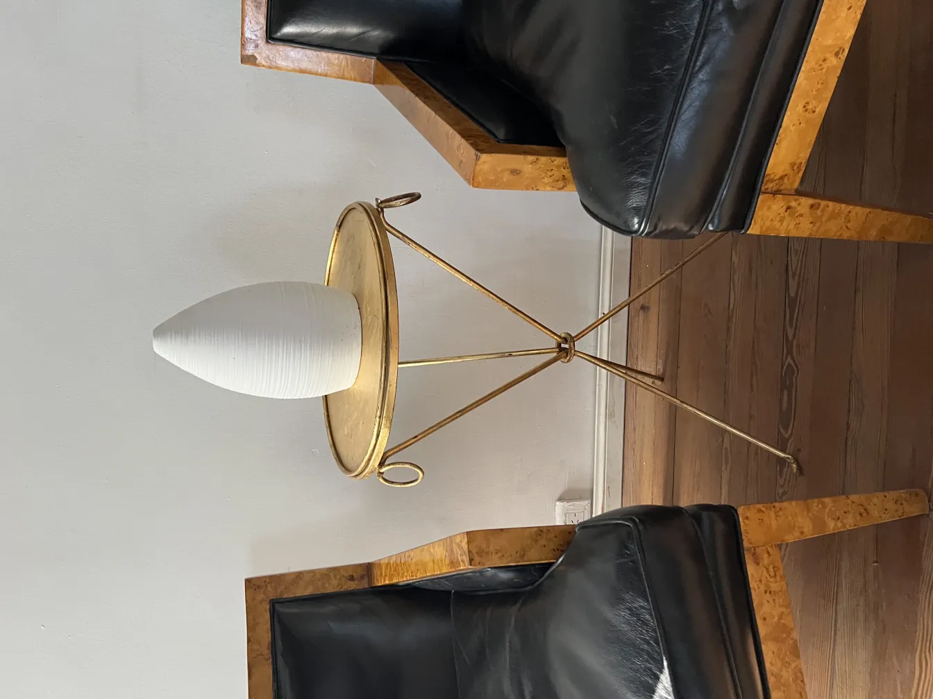 Céramique ancienne sur une table dorée avec des fauteuils noirs.