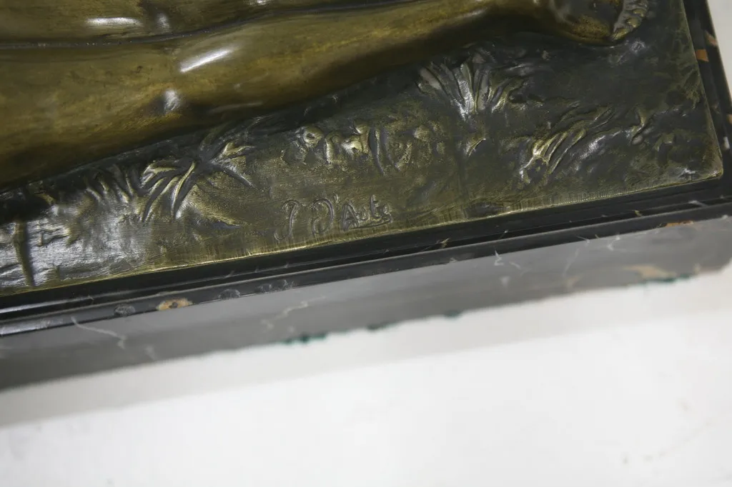 escultura antigua con detalles de plantas y figuras, firmado