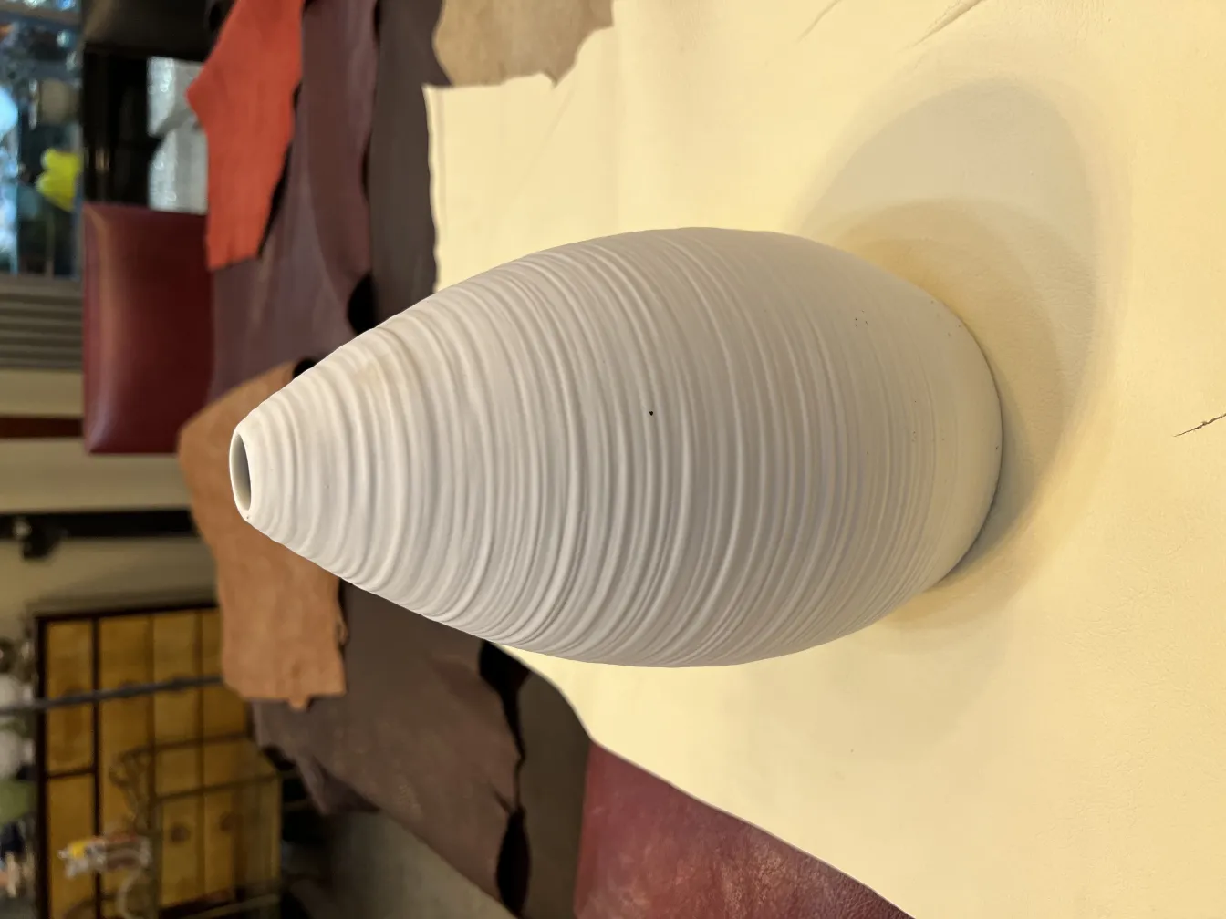 Antike weiße Keramikvase mit Textur auf einem Lederhintergrund.