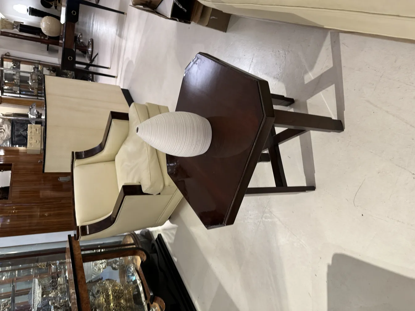 Elegante vaso in ceramica su un tavolo di legno, con una sedia sullo sfondo in un ambiente antico.