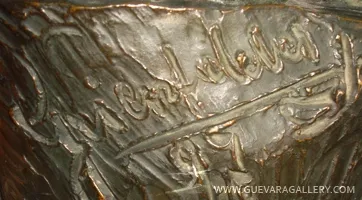 Detail einer antiken Skulptur mit sichtbarer Unterschrift.