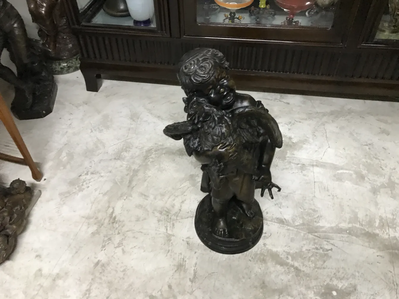 Skulptur eines Engels, der ein Kind in einer antiken Umgebung hält.