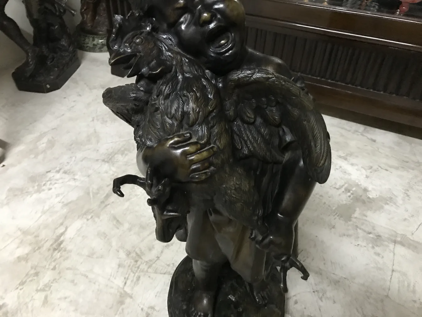 escultura antiga em bronze de um homem segurando um pássaro