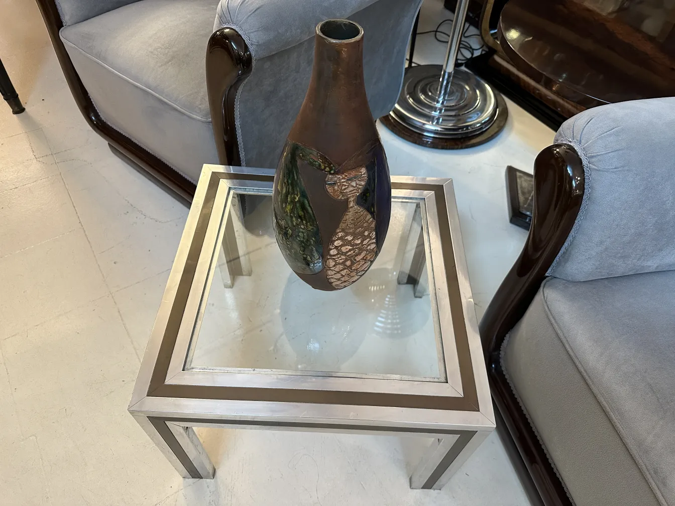 Antigua cerámica decorativa en tonos marrones y verdes, con diseño artístico frente a un sofá