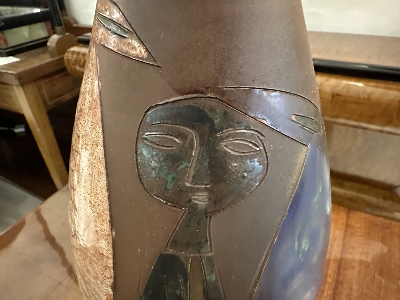 cerâmica antiga com design de figura humana em tons terrosos e azul