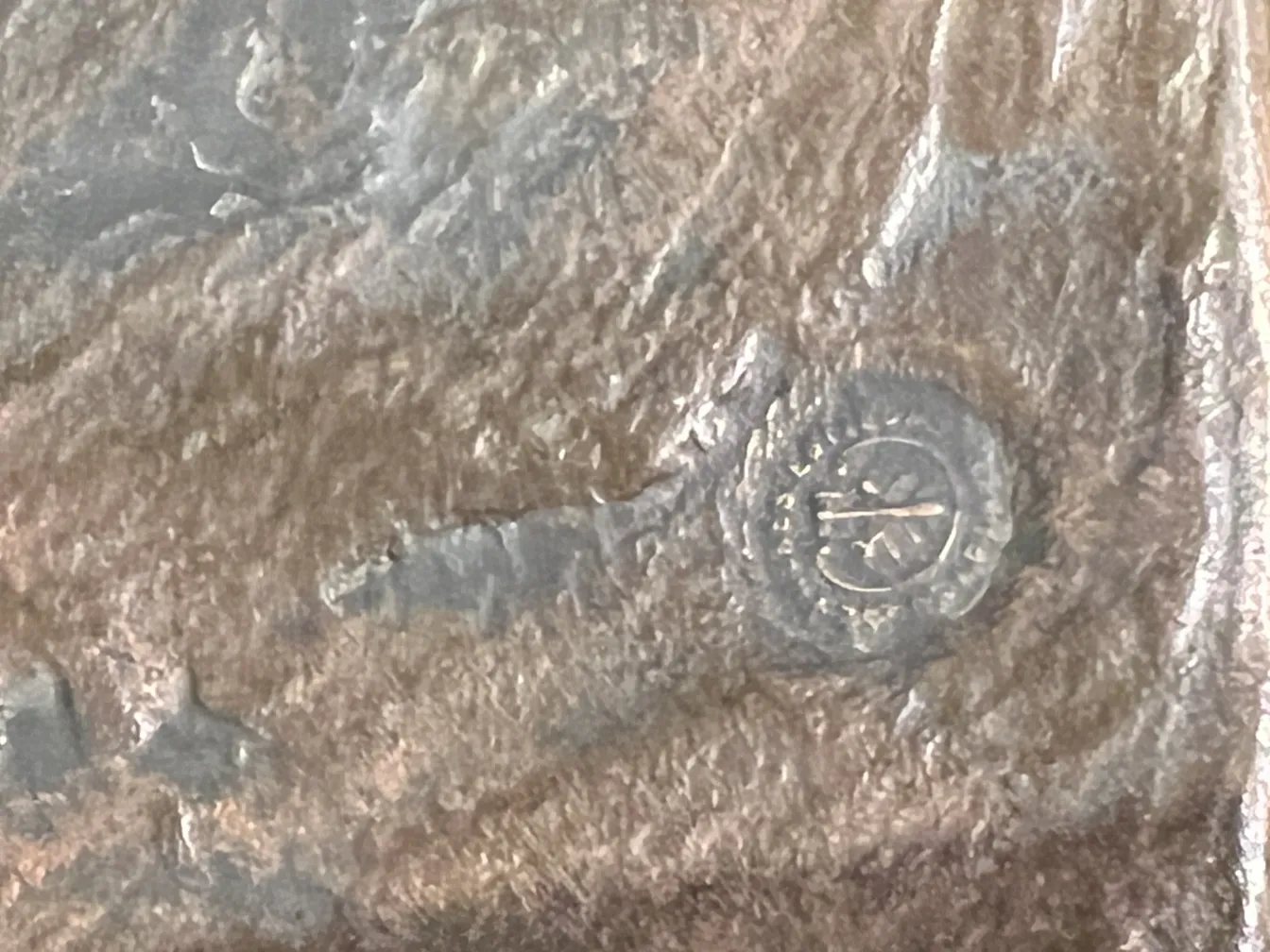 Scultura antica con finitura texturizzata, dettagli visibili e un ambiente classico.