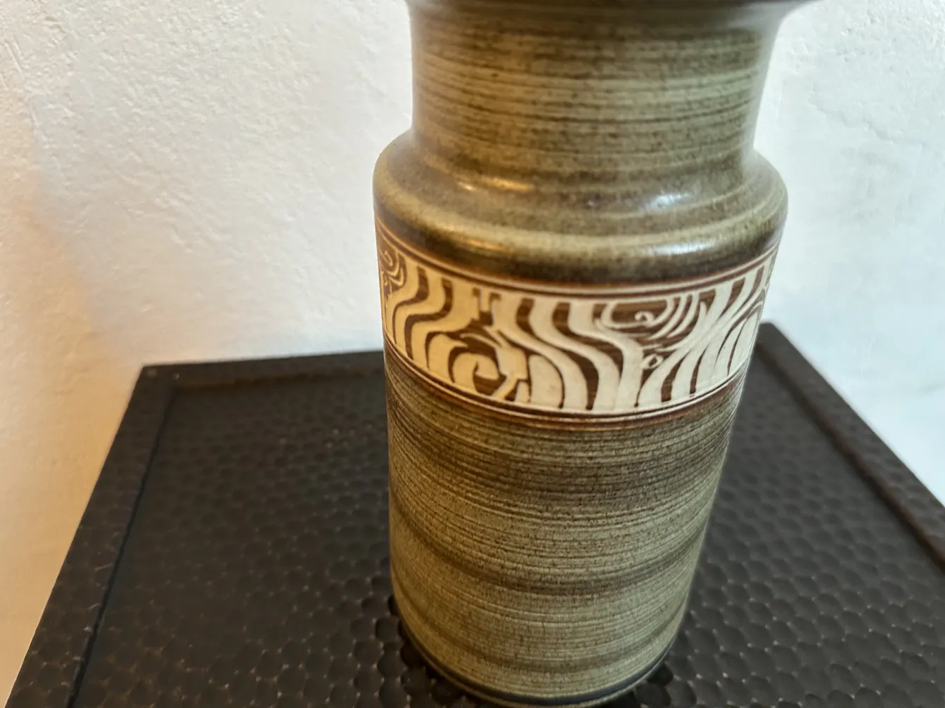 Antigua cerámica gris con diseño en relieve en la parte media.